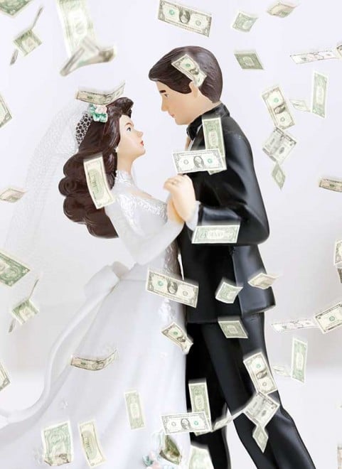 Dollar banknotes falling on bride and groom figurines