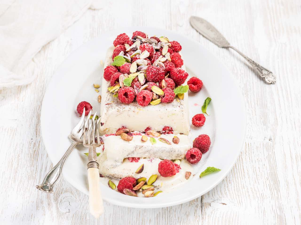 Raspberry recipes: Homemade semifreddo with pistachio and raspberry in oval dish over old white painted wooden background, selective focus, horizontal composition