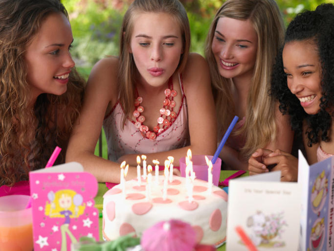 teen girl blows out birthday candles on cake