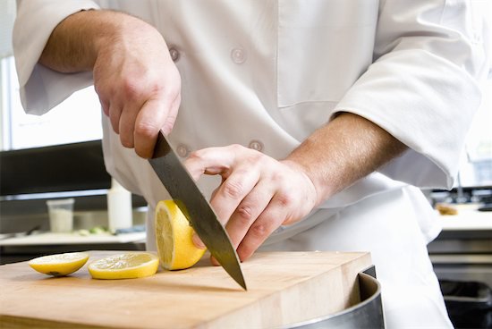 chef cutting with knife on slicing lemon on cutting board