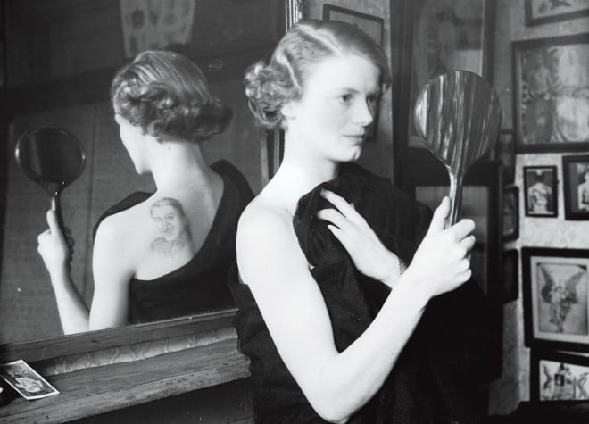 black and white photo, woman looking at her tattoo in the mirror