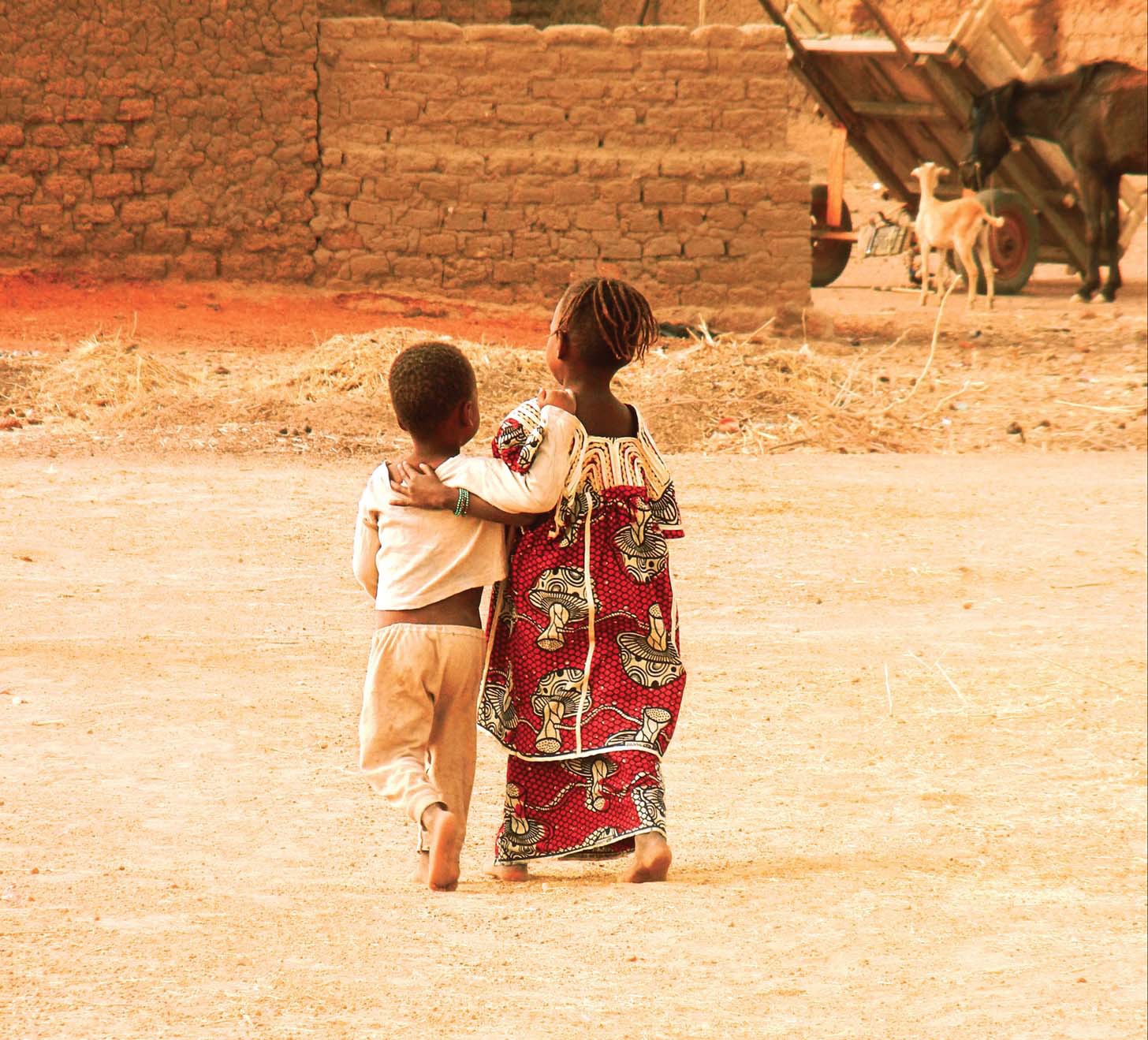 Two Malian children walking on dirt road