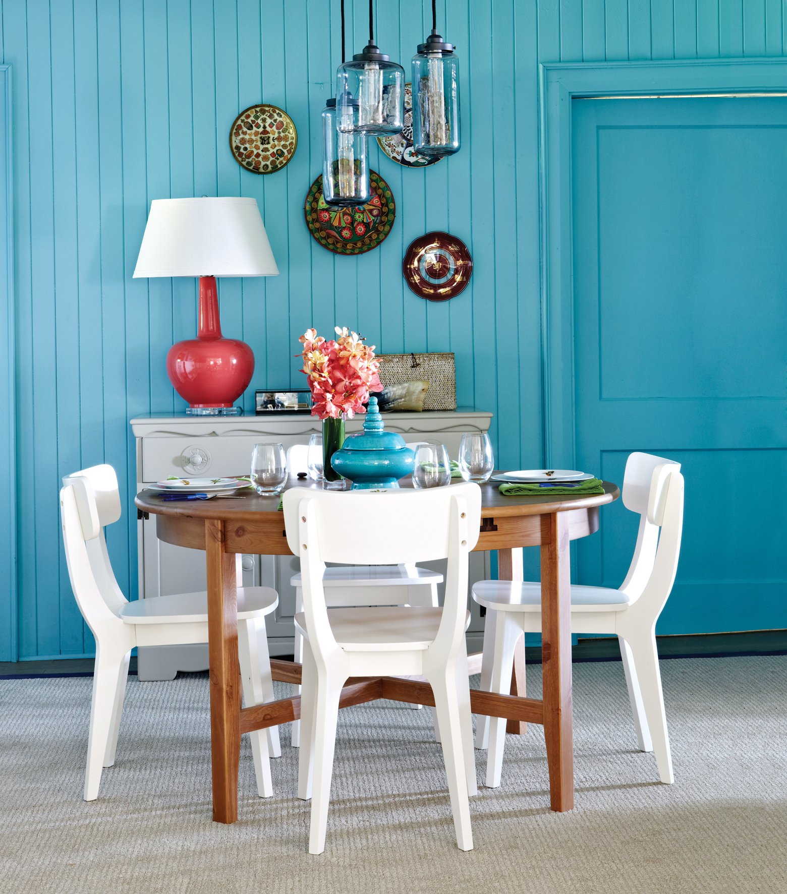 Blue dining room, would table, white chairs, pink lamp, flowers
