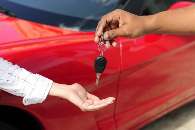 woman receiving car key from salesman, car debt
