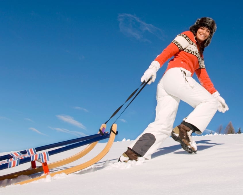 Woman pulling a tobaggan sled up a hill