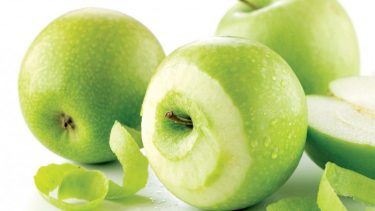 Green apples that have been partly peeled by a vegetable peeler