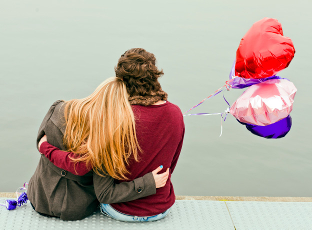 A young couple hugging and holding balloons