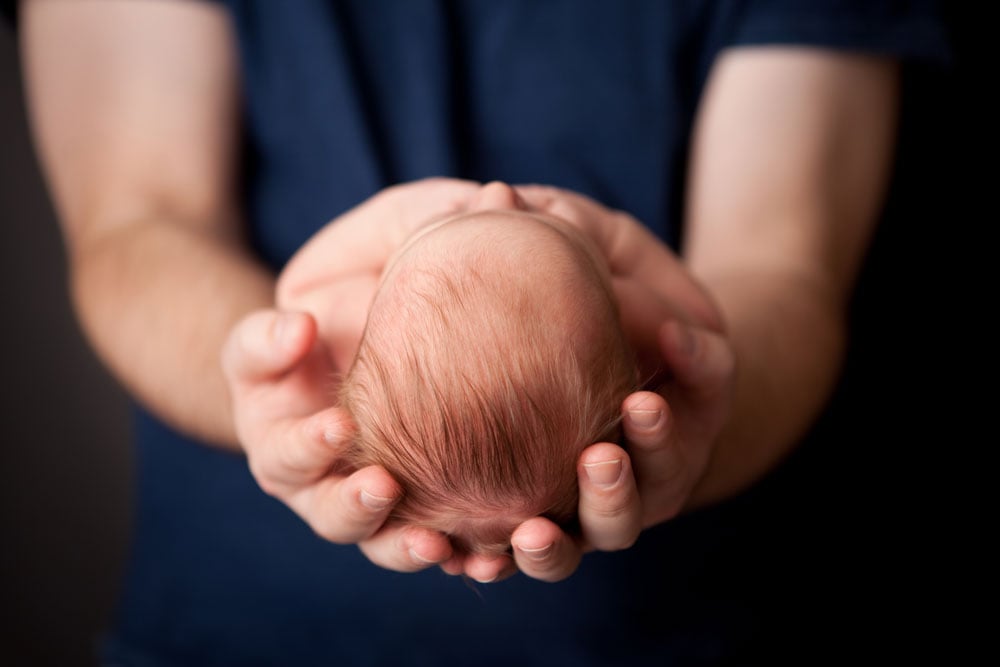 A baby rests in his father's hands