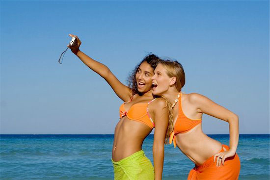 Two women take their own photo on the beach