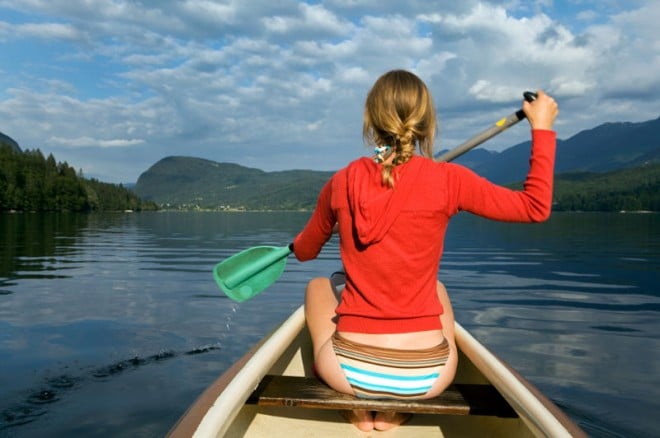 A blonde woman canoeing in the lake in nature