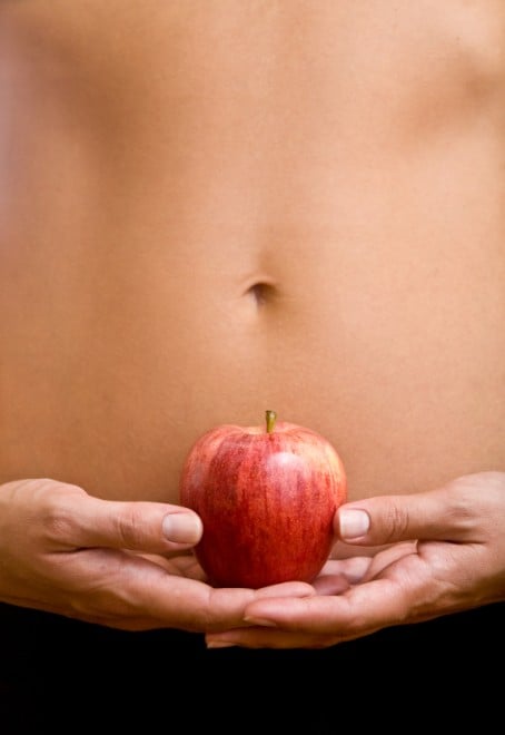 A woman with a flat stomach holding an apple