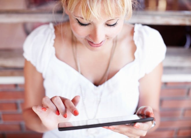 A blond woman browses on an iPad
