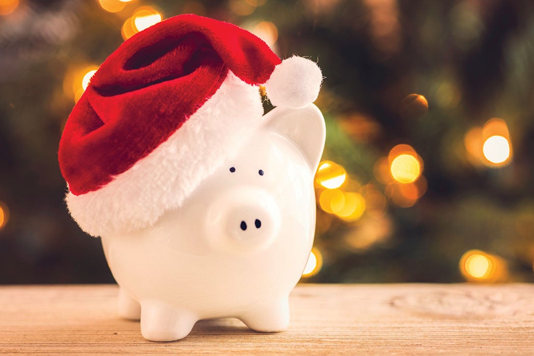 Piggy bank with Santa hat and Christmas tree in the background