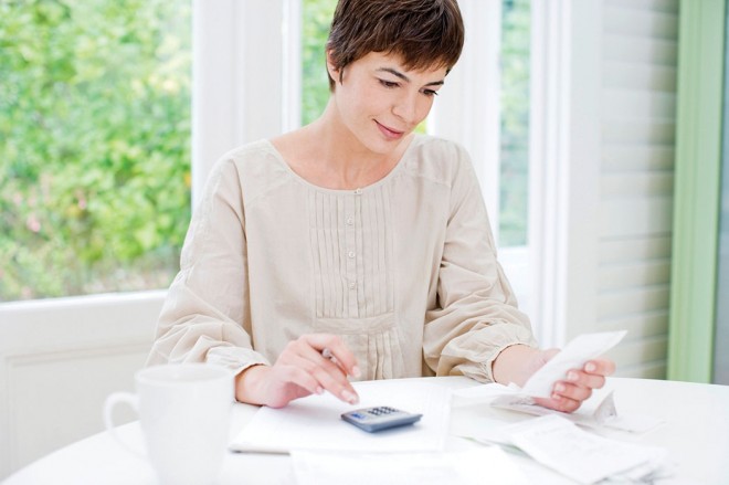 Woman calculating doing math or taxes on a calculator calculating personal finance and money