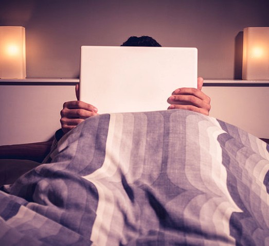 Man watching porn on computer in bed