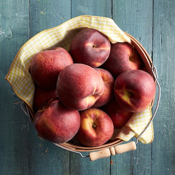 How to peel peaches: Large bowl of fresh peaches on w wooden table