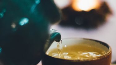 benefits green tea - a teapot pours tea into a mug