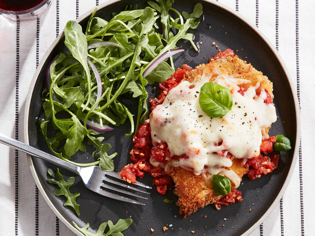 quick chicken parmesan and arugula salad on a black plate