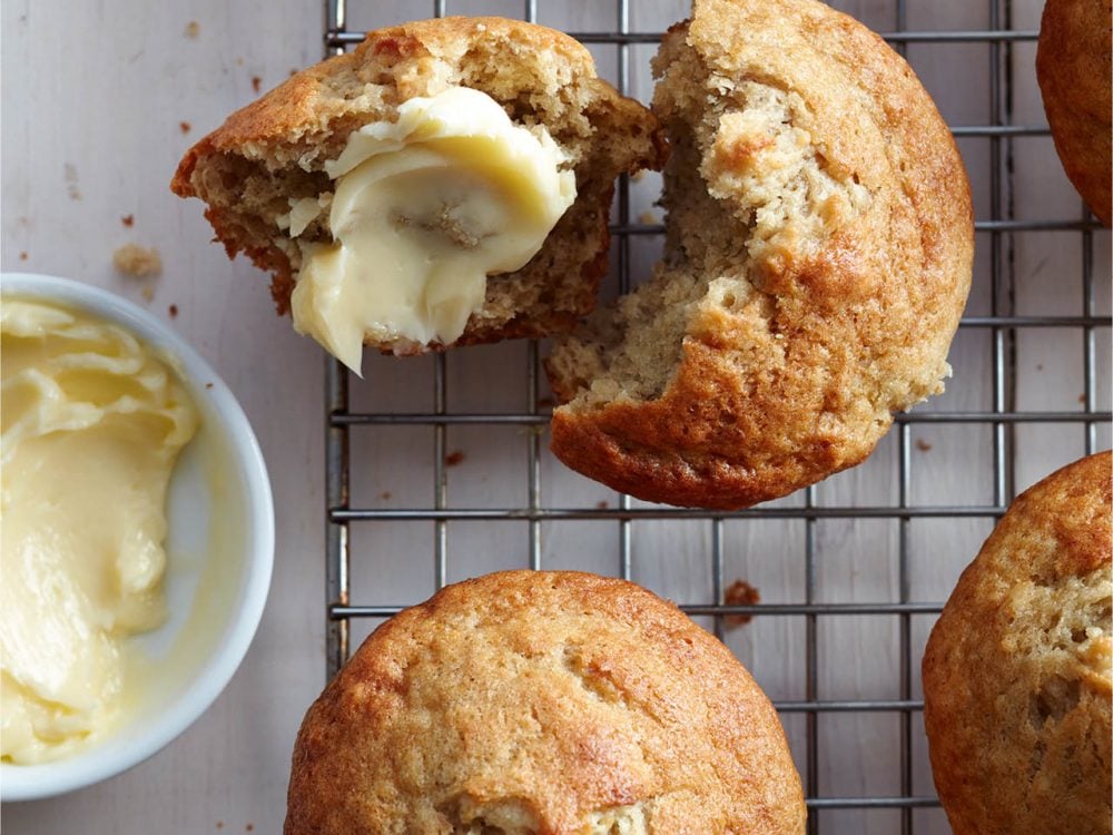 Banana muffins on a cooling rack with a dish of butter