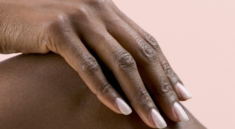 Nail health - a girl with nice nails rests her hand on her knee