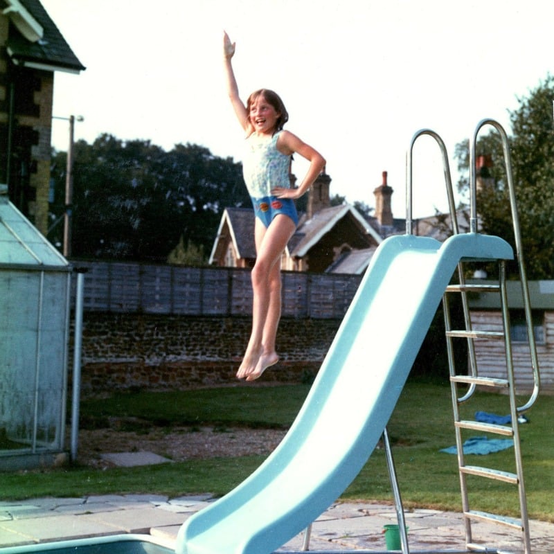 <p>Diana jumps off the slide into the swimming pool at her family’s home at Park House. Her swimming badges are sewn on to the bottom of her bathing suit.</p>
