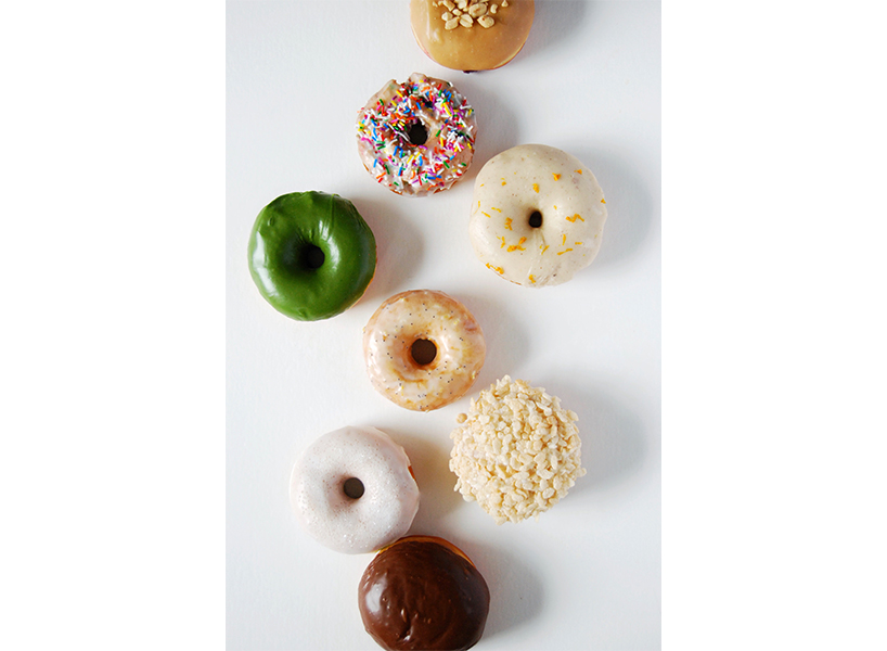 Half a dozen varied doughnuts from Bronuts in Winnipeg sit on a white table.