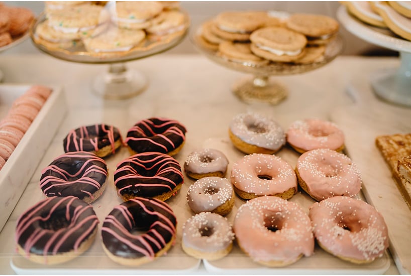Assorted frosted doughnuts sit in a white display case at Pretty Sweet in Calgary.