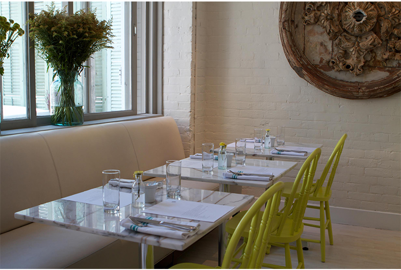 Netral walls, set tables, and green chairs at Wish brunch spot in Toronto.