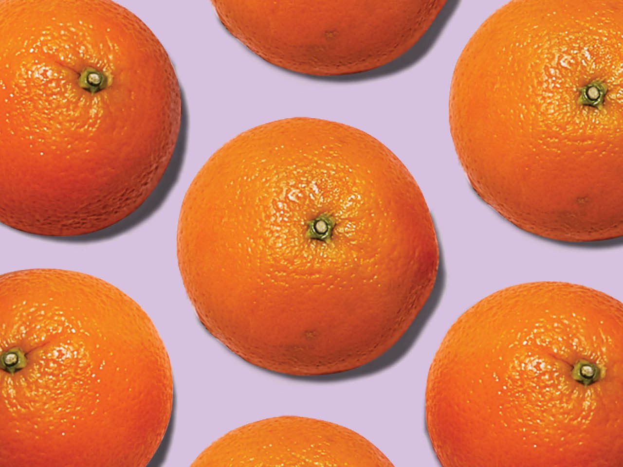 Oranges cut in half sit on a purple background - can oranges reduce dementia?