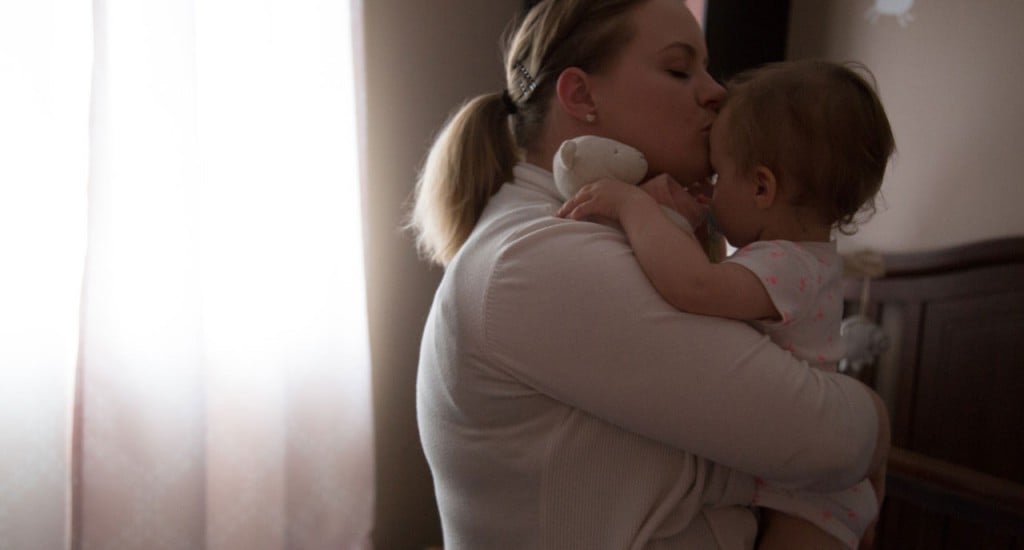 An opioid-dependant mother holds her baby Everley and gives her a kiss on the forehead.