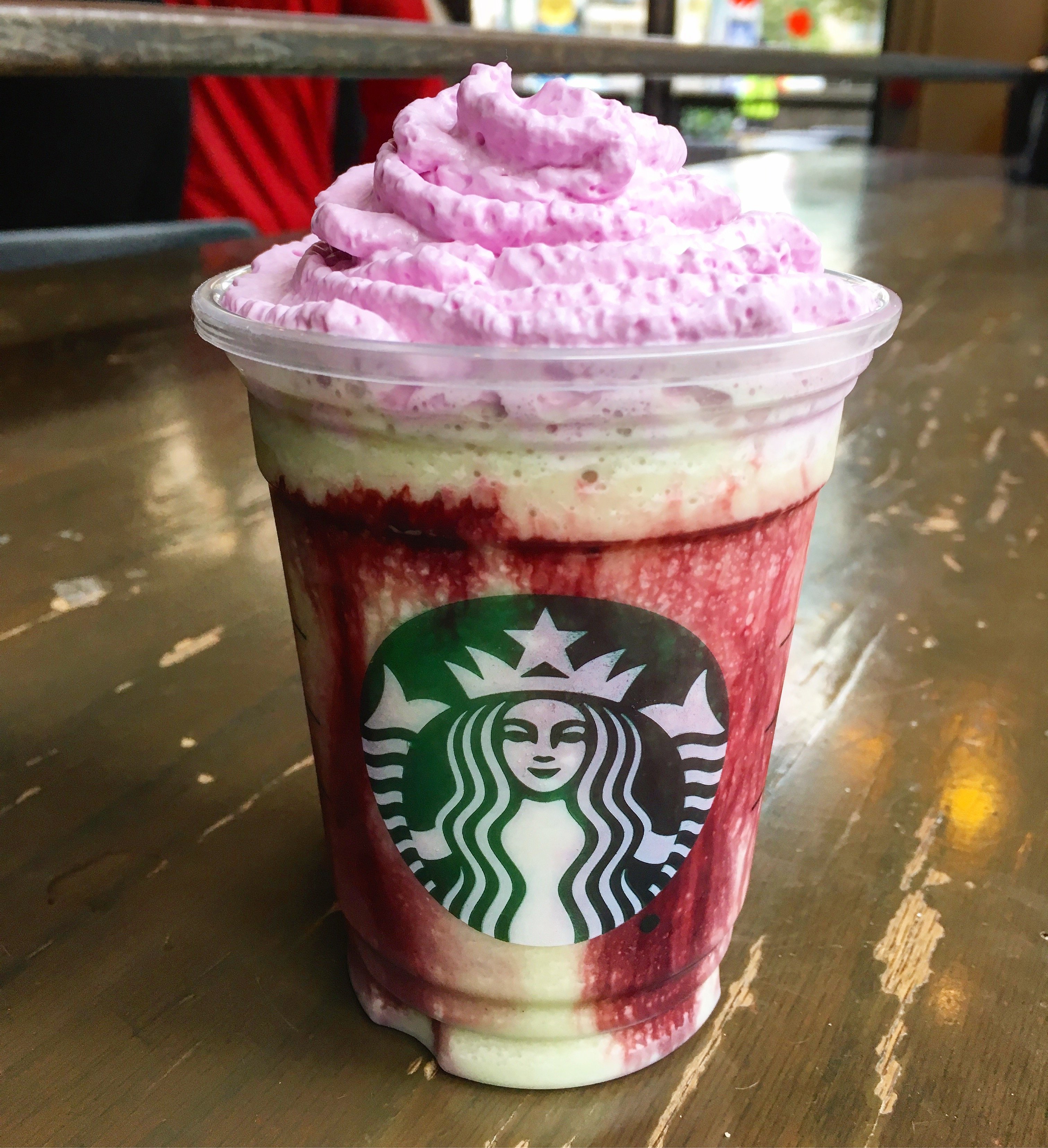 Starbucks Zombie Frappuccino with pink whipped cream on wooden table