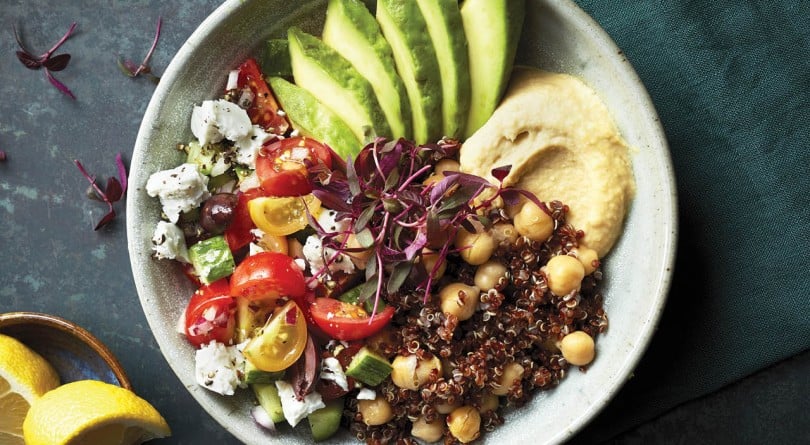 how to cook quinoa: mediterranean quinoa bowl with hummus, avocado and fresh tomatoes in a white bowl