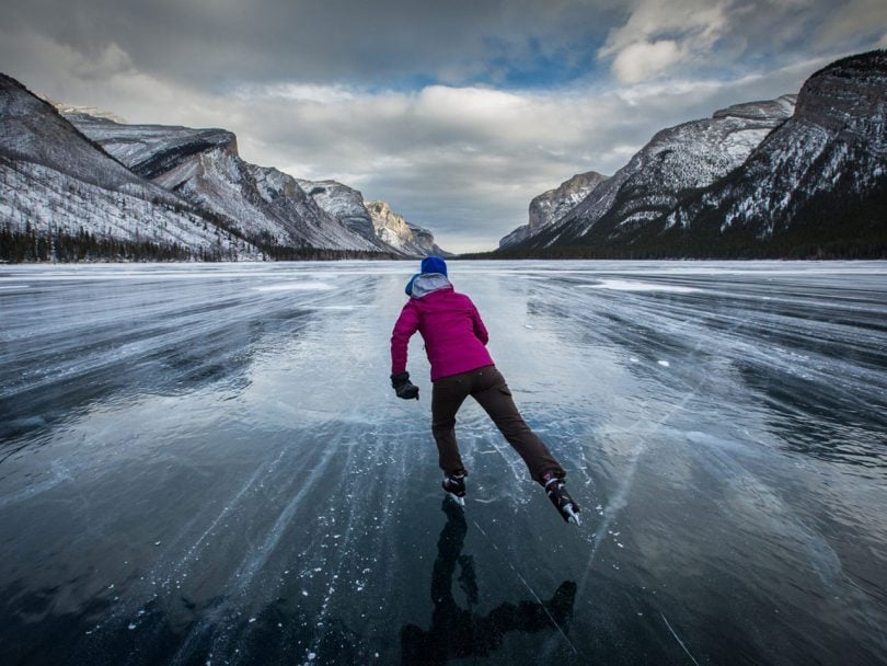 photo of woman skating on frozen lake louise with mountains in the background for best skating rinks in canada post