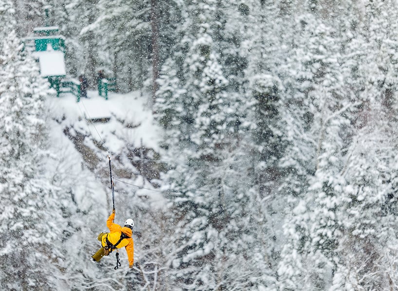 best outdoor winter activities- a man in a yellow ski jacket ziplining in newfoundland