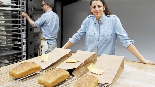 Crop Diversity-Jane Rabinowicz of USC Canada stands in a test kitchen with 3 loaves of great made from different grains.