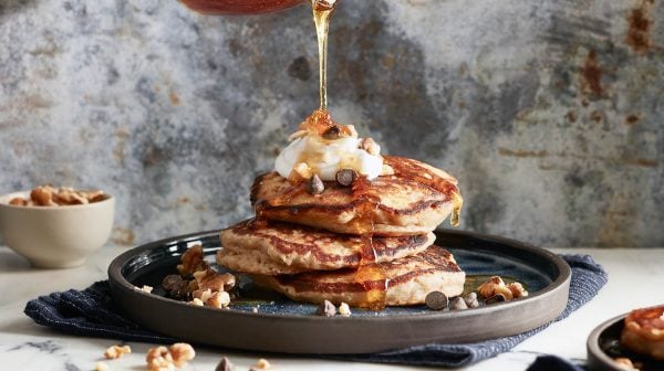 a stack of banana bread pancakes with syrup being drizzled overtop