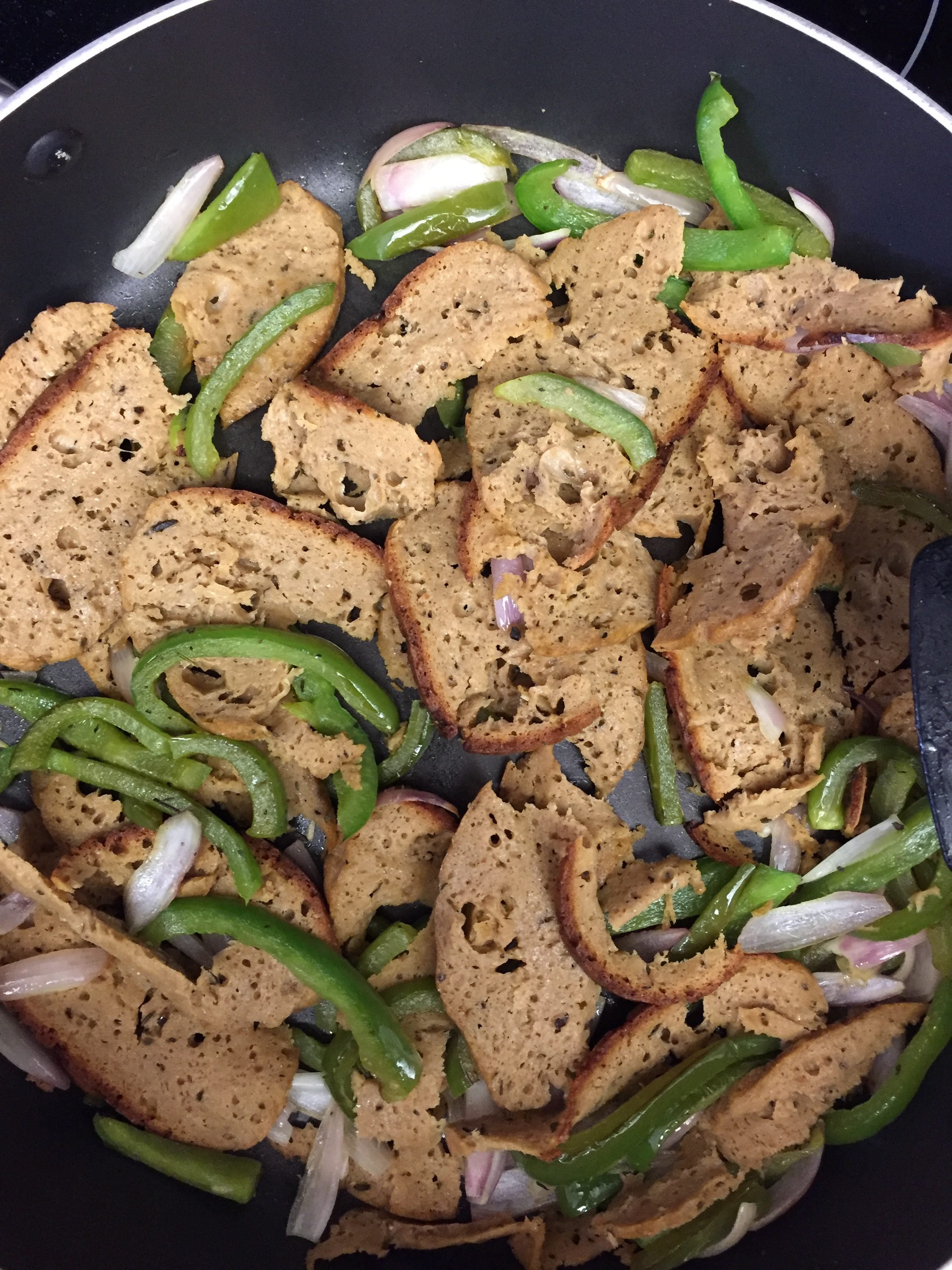 Seitan and green peppers in a pan.