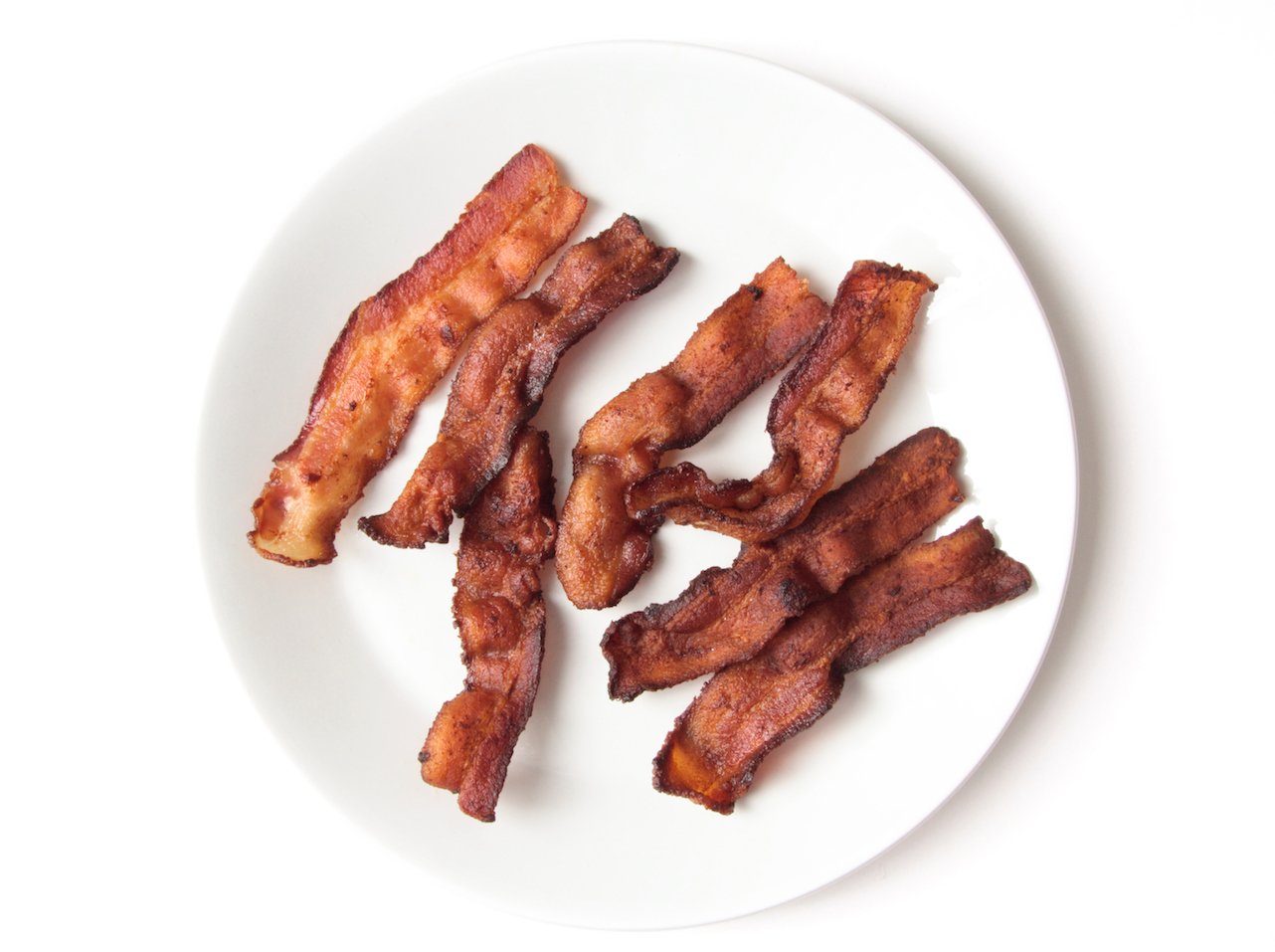 crisp bacon on a white plate (cook bacon in the oven for perfect results)