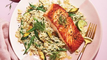 Pink plate topped with orzo and salmon.
