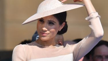 Meghan Markle at a garden party. Markle is wearing a hat