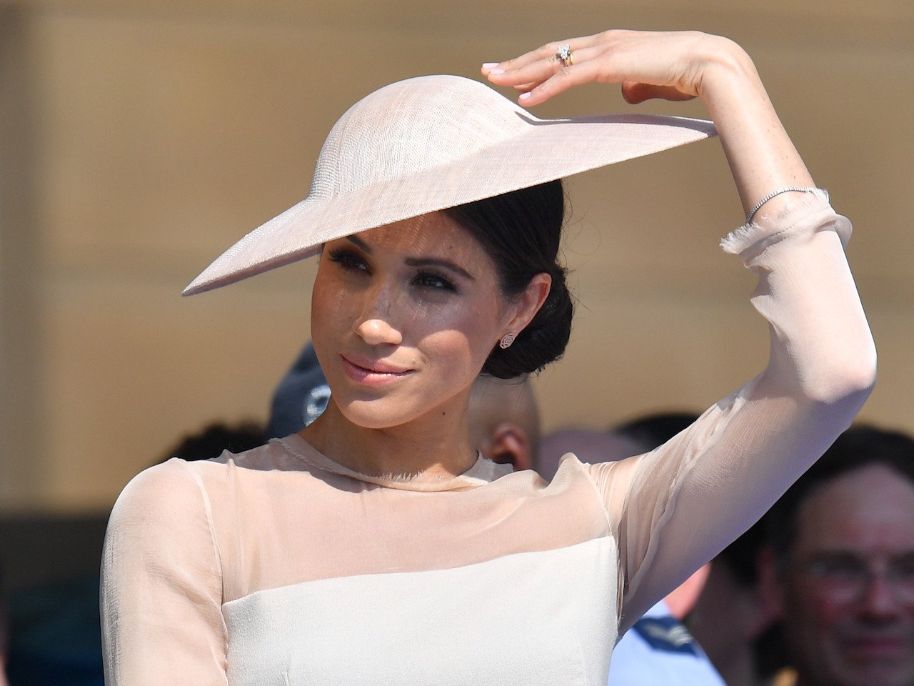 Meghan Markle at a garden party. Markle is wearing a hat 