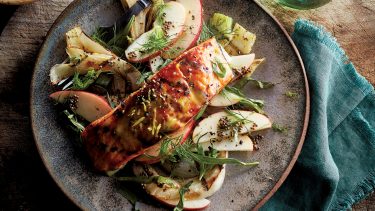 Grilled salmon on a grilled apple salad served on a grey plate