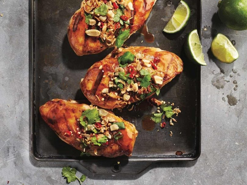 Best way to cook chicken breast: Three chicken breasts covered with peanuts and parsley on baking sheet.
