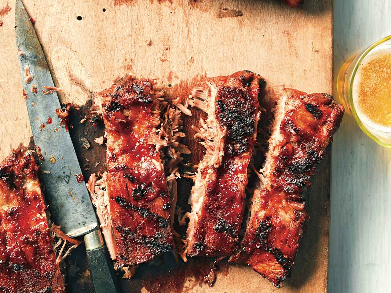 Saucy grilled pork ribs on cutting board.