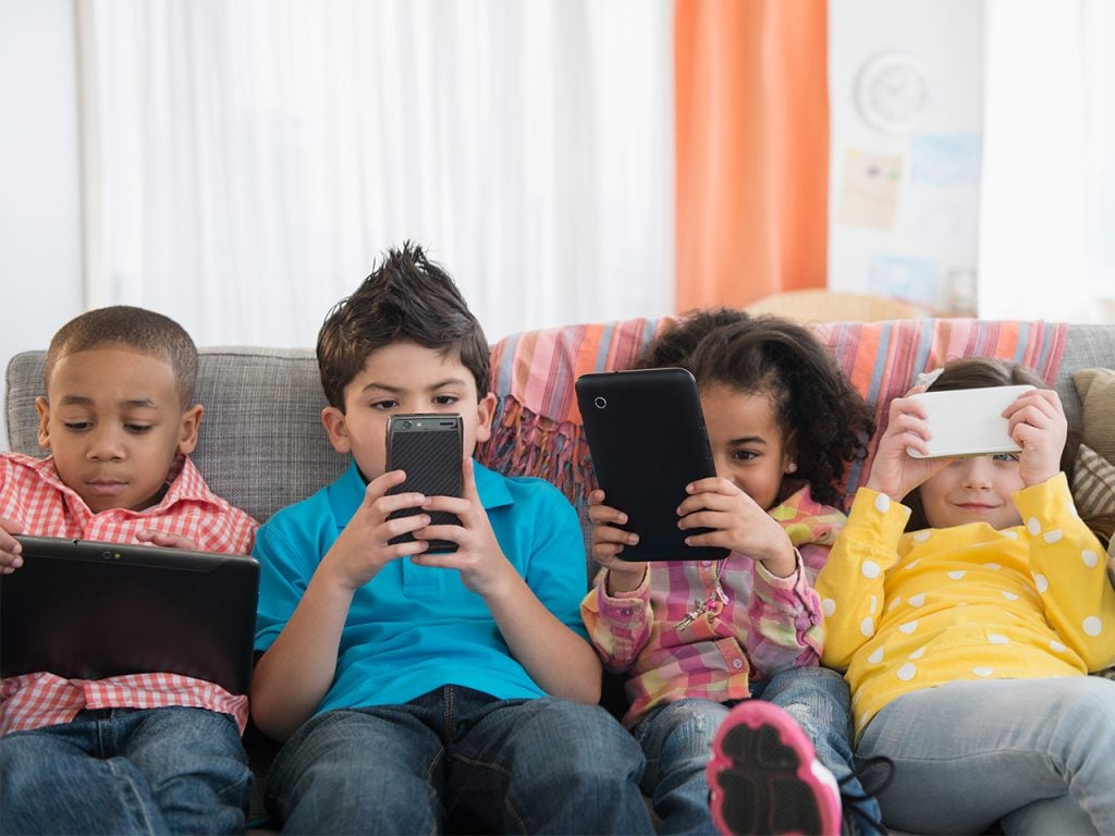 children using technology on sofa