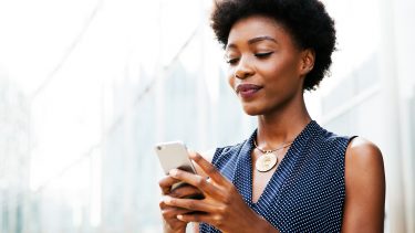 Woman looking at mobile phone. Should you trust budgeting apps like Mint?