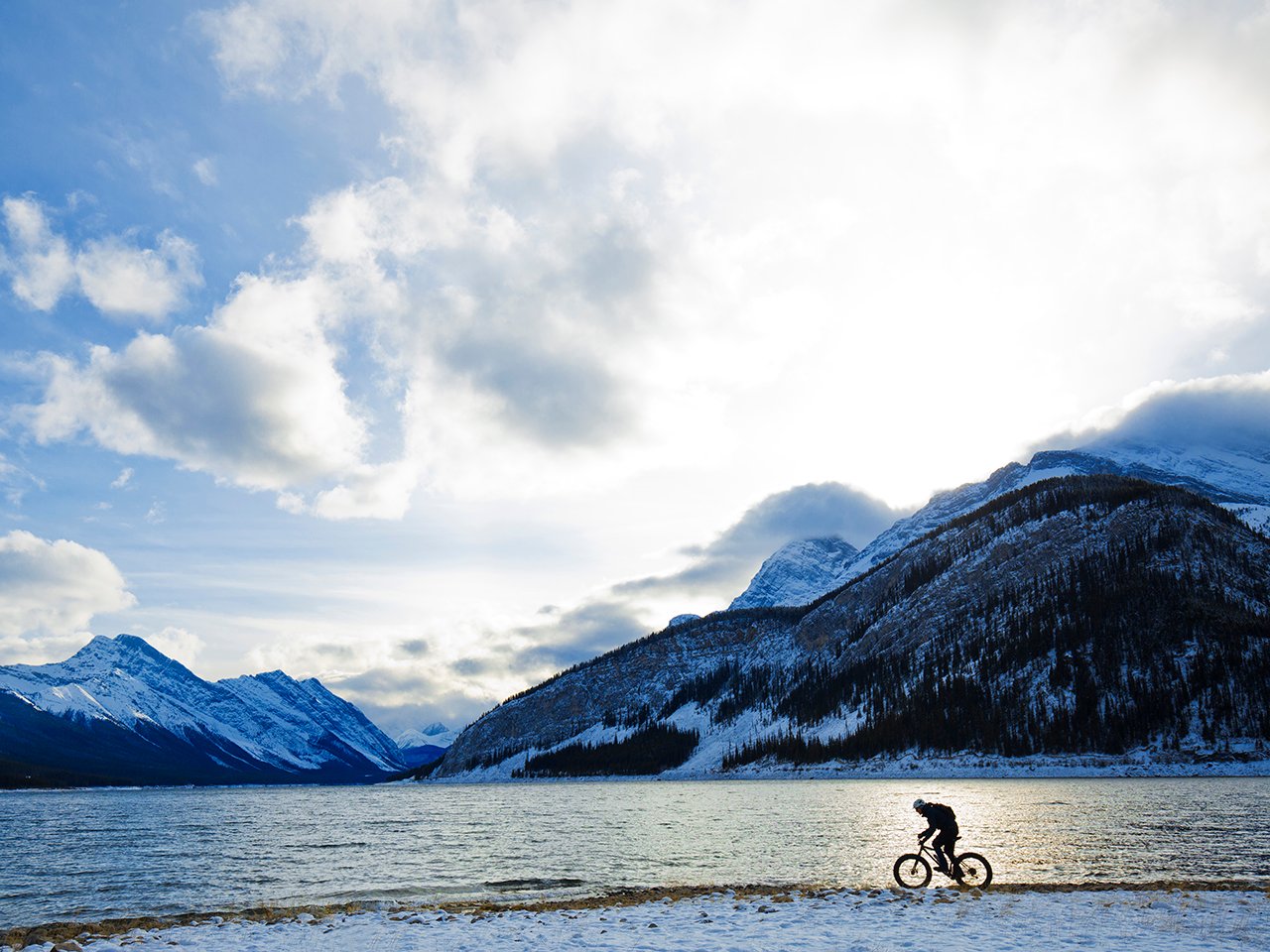 A man rides a bike ride along a lake in the Canadian Rockies. Here are 5 things you can do to fight climate change
