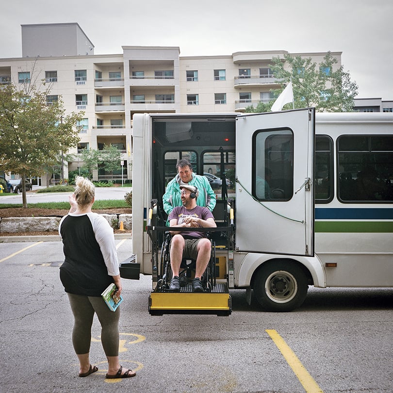 early-onset Alzheimer's at 41-Jo getting off the bus in a wheelchair lift as wife Robin greets him.