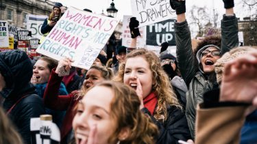 women shouting and holding placards at TimesUp march in London, England