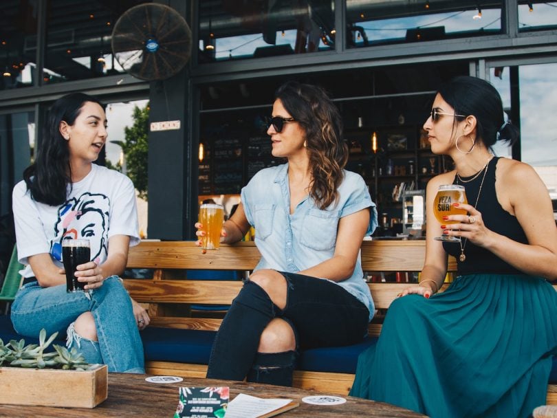 guilt-three women sit gossiping over beers